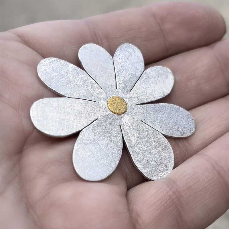 Blütenanhänger aus Silber in einer Hand